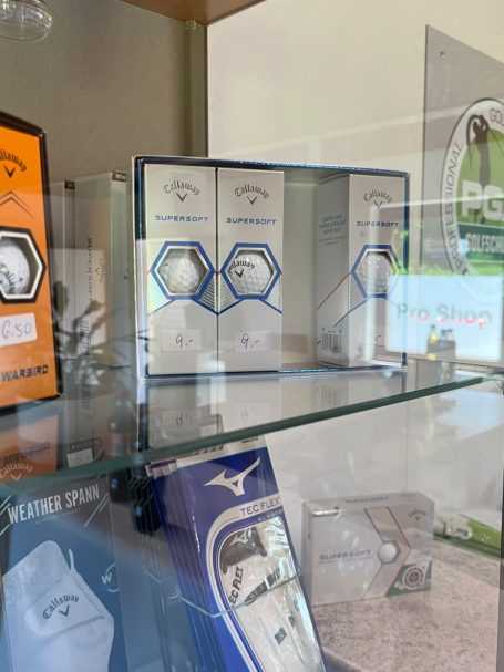 Golfbälle und Golfzubehör in einem Golfgeschäft, angeordnet in einer Vitrine