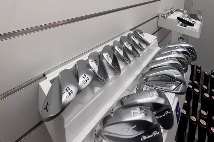 Eine Reihe von Mizuno Golf-Schlägern mit nummerierten Köpfen auf einem Regal.