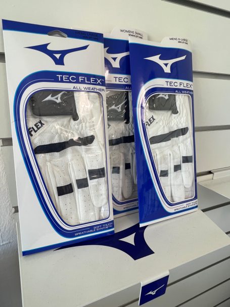 Golfhandschuhe und Golfzubehör in einem Golfgeschäft, angeordnet an Wänden mit Regalen.