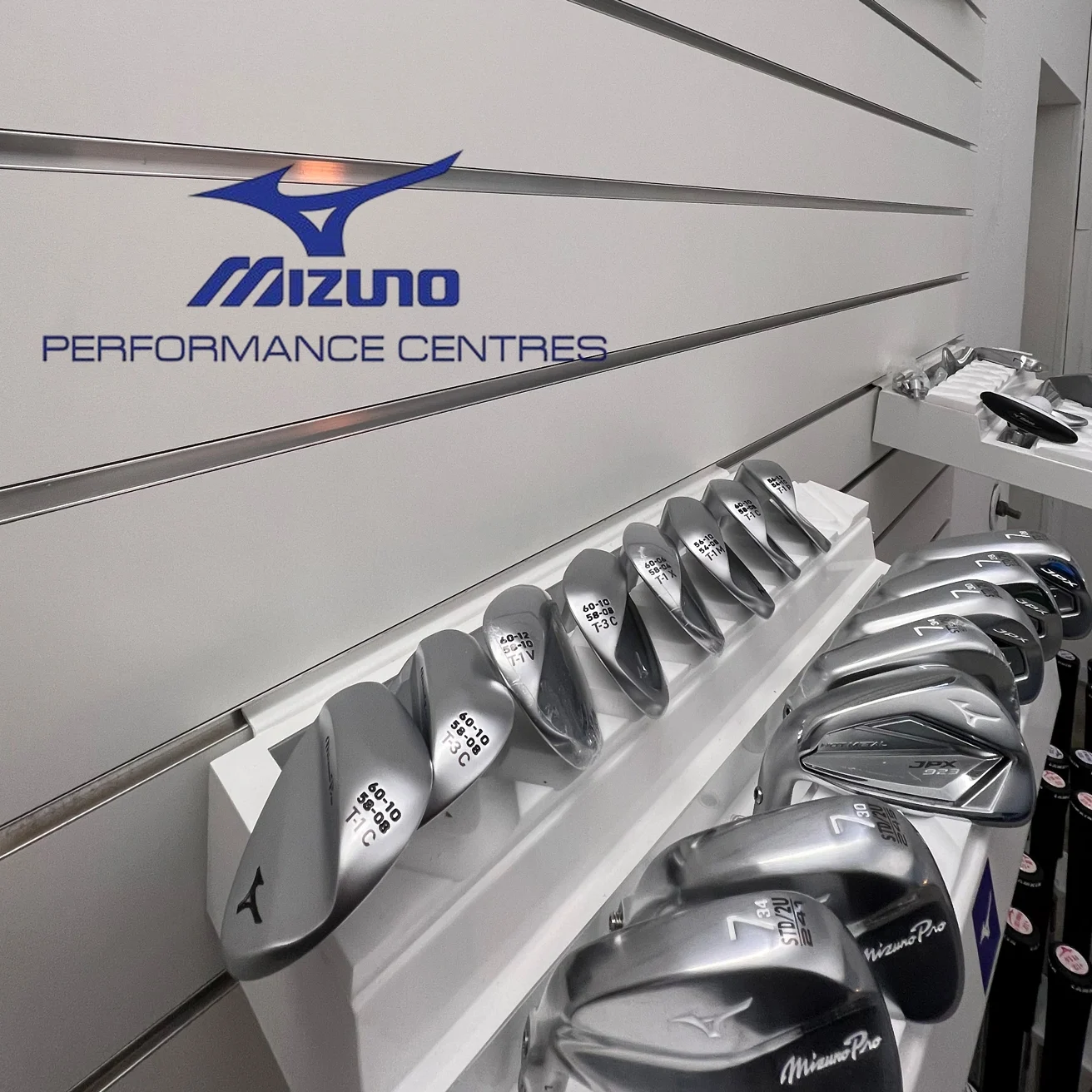 Mizuno Golf-Schläger auf einem weißen Regal, beschriftet mit "Mizuno Performance Centres".